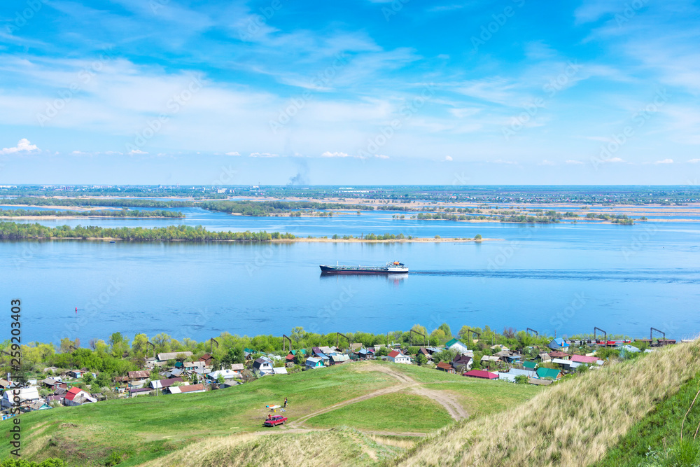 view from the cliff to the Volga river, suburban buildings, coastline, tanker going along the river