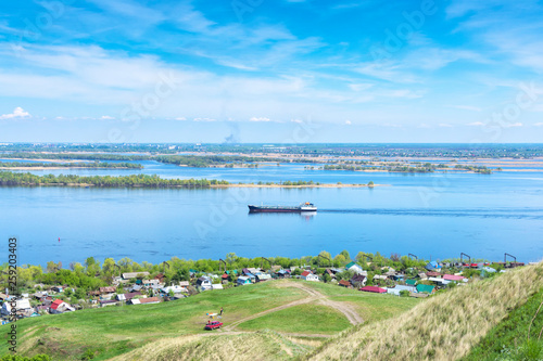 view from the cliff to the Volga river, suburban buildings, coastline, tanker going along the river