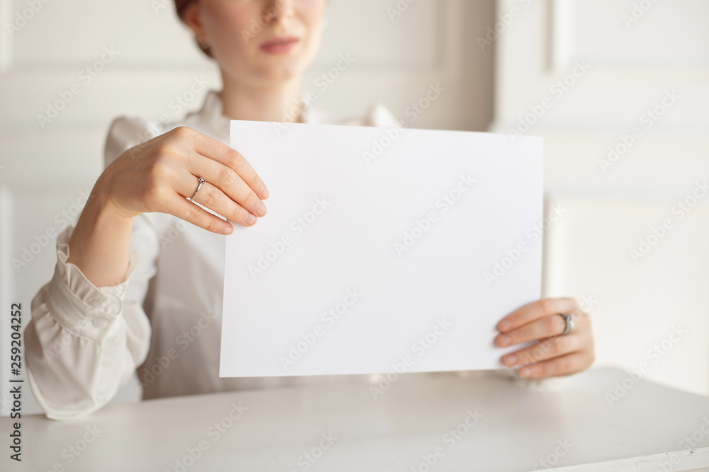 Woman holding white business card on white wall background. Woman holding white business card on white wall background.