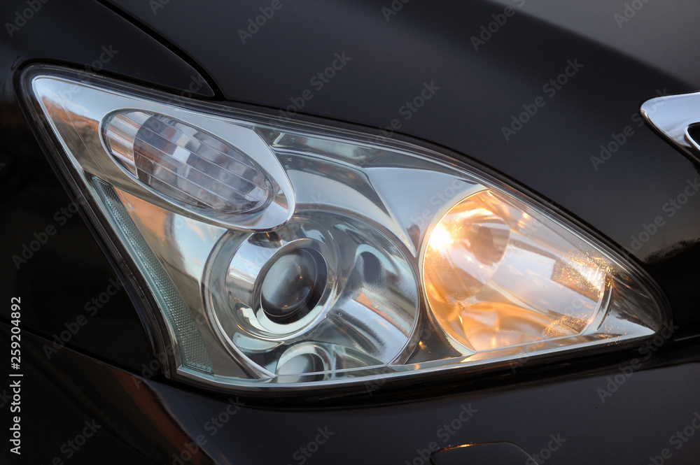 headlight of the main light of the black car, close-up.