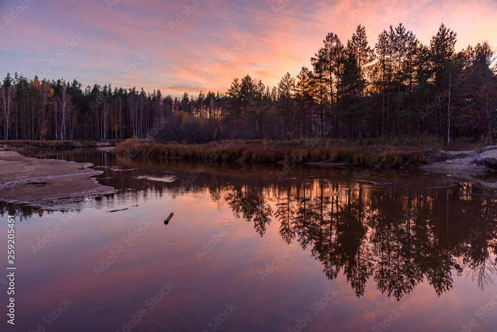 Smooth surface of the water in the river. Reflection in the water of trees, forest and sunset Smooth surface of the water in the river. Reflection in the water of trees, forest and sunset