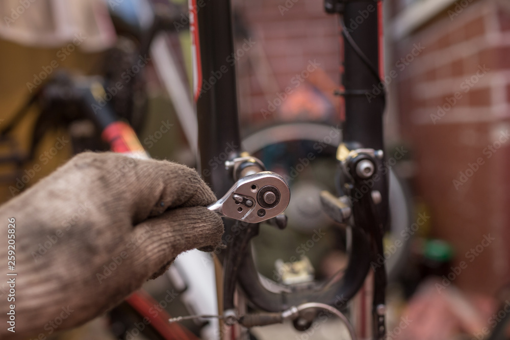 Obraz premium worn brake pads. male mechanic making service in bicycle repair shop, repairman fixinig bike brakes using special tool