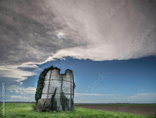 View of ruined windmill against cloudy sky photo