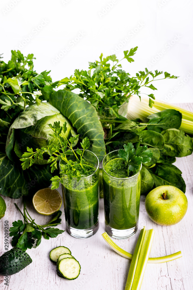 Green smoothie with fruits and vegetables on white wooden background. Green smoothie with fruits and vegetables on white wooden background.