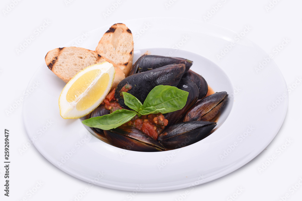 mussels in a plate in tomato sauce with lemon and toast on a white plate