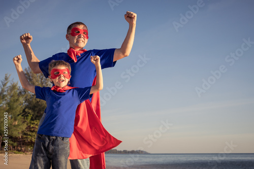 Father and son playing superhero on the beach at the day time.