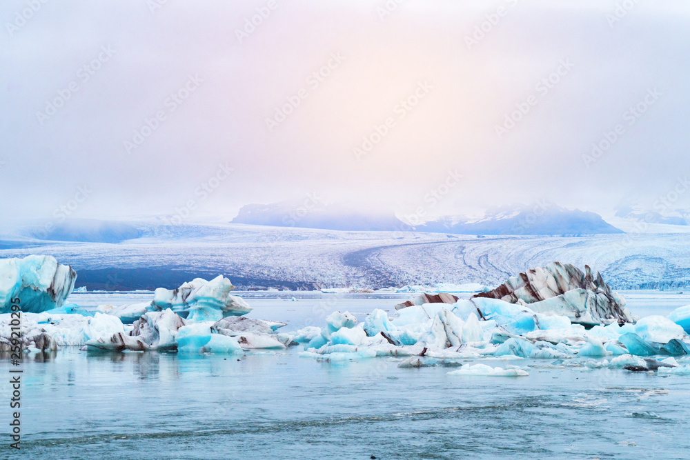 Luminous blue icebergs  floating in Jokulsarlon glacial lagoon with background of glacier mountain. South Iceland, VatnajÃ¶kull National Park. Copy space background. Place for text.