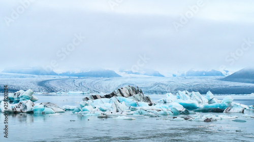 Luminous blue icebergs  floating in Jokulsarlon glacial lagoon with background of glacier mountain. South Iceland, VatnajÃ¶kull National Park. Copy space background. Place for text. photo