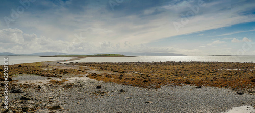 Panorama image, path from Hare island, Galway, Ireland. Sunny day, Very low tide. blue sky and the Atlantic ocean. Small path to the island is visible.