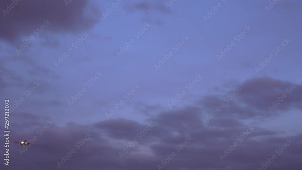 Passenger plane flies in the sky. Preparing to go to the landing. In the background evening purple sky. Clouds of beautiful shapes. Passenger plane flies in the sky. Preparing to go to the landing. In the background evening purple sky. Clouds of beautiful shapes.