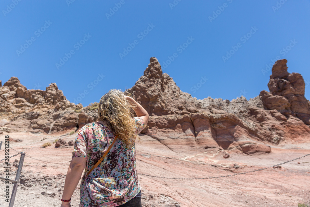 A blond tourist woman looks carefully at some volcanic rocks in the Teide National Park, Canary Islands