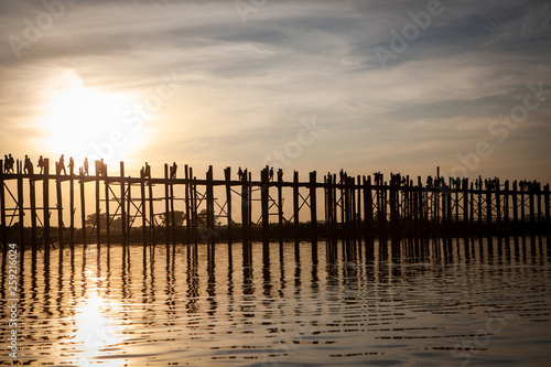 Sunset over U Bein Wooden bridge with locals' and tourists' silhouettes, Mandalay, Myanmar
