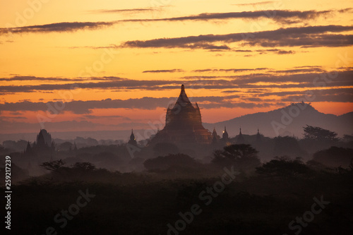 Beautiful sunrise over the ancient pagodas in Bagan  Myanmar. Orange sky and fog between the hills