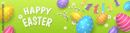 Vector cute horizontal greeting banner with garland of paper-cut bunnies and colored 3D realistic eggs. Festive template with text Happy Easter, paper chamomiles and pussy willow on green background.