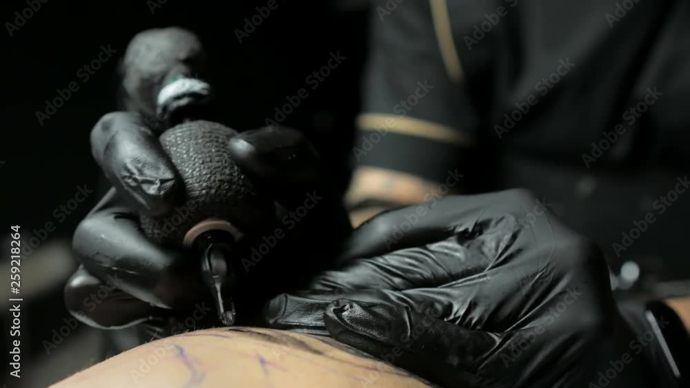 Tattoo artist makes a tattoo on a man's hand Tattoo artist makes a tattoo on a man's hand