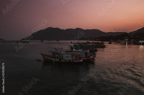 tranquil scene of fishing boats during sunrise in a bay in Koh Tao, Thailand
