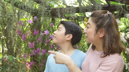 Happy asian family mother and son walking in the orchid garden with smile face.