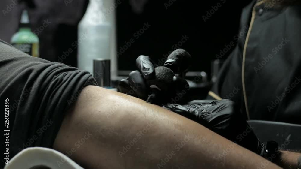 Tattoo artist makes a tattoo on a man's hand Tattoo artist makes a tattoo on a man's hand