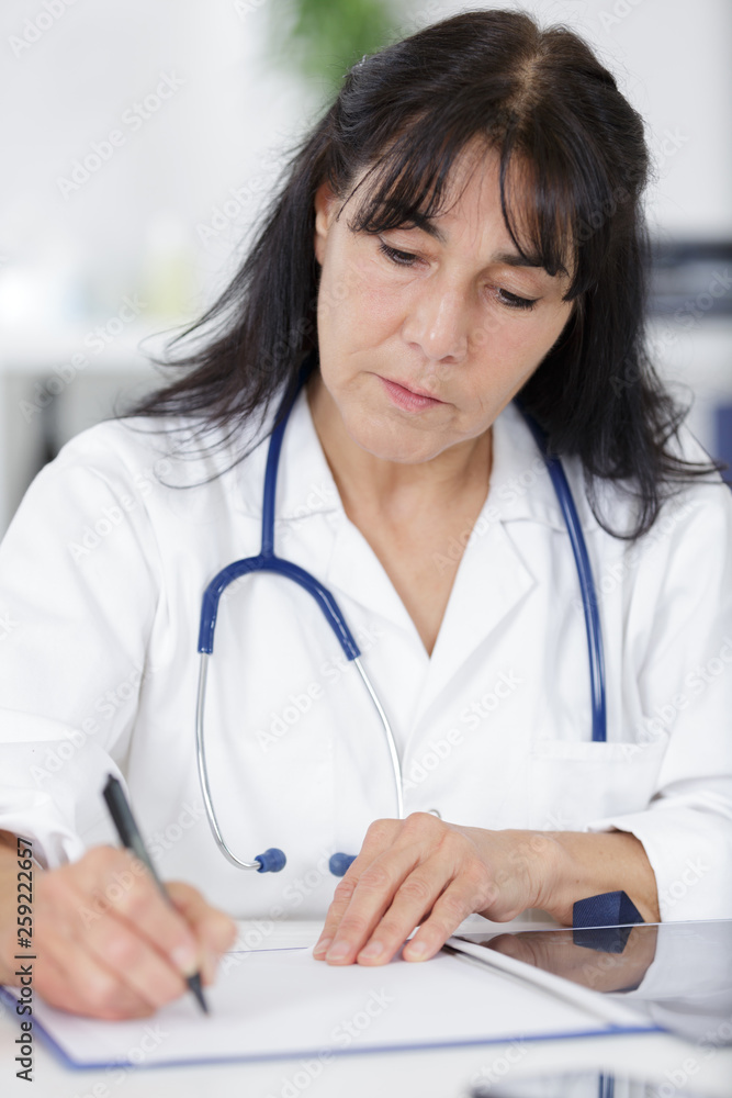 mature woman doctor write prescription in office mature woman doctor write prescription in office