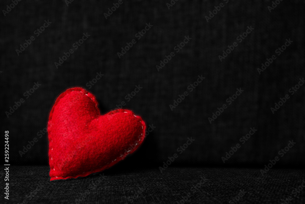 Obraz premium Red valentines day heart made from wool on dark fabric background. Concept of love 