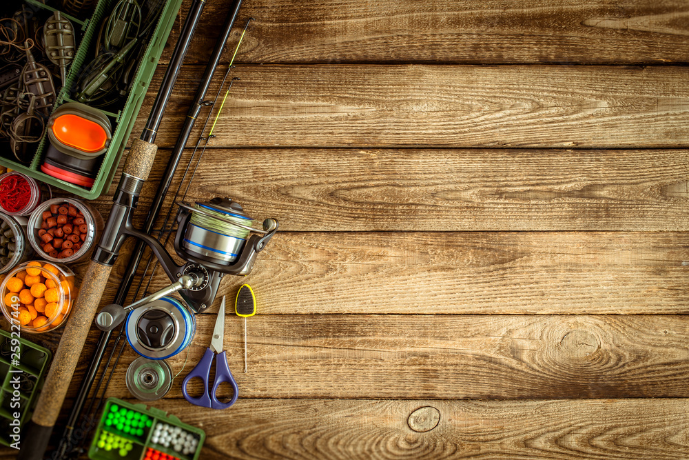 Fishing feeder and reel.Fishing tackle background.Fishing feeder- hooks and lures on darken wooden background. Fishing feeder and reel.Fishing tackle background.Fishing feeder- hooks and lures on darken wooden background.