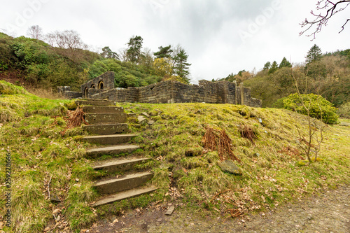 A view of ruin site around green vegetation and trees under a white cloudy sky