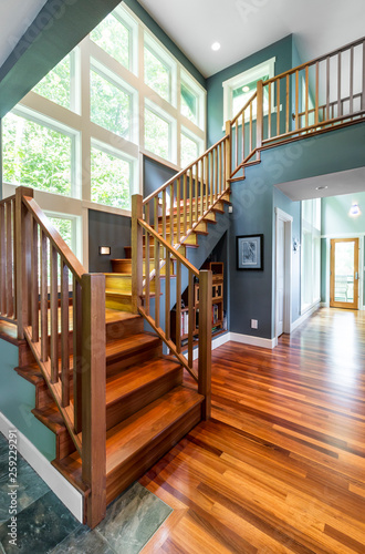 Beautiful, high quality, contemporary home interior with hardwood flooring floors, wooden staircase, vaulted ceiling, painted walls and big windows