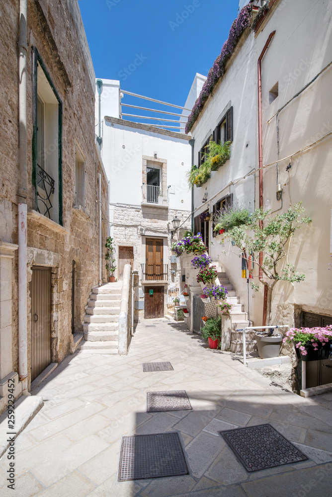 Narrow, small and romantic stairs and streets of Italy. White buildings in old town with flower decorations in front of apartments and houses. Beautiful, fresh summer morning. Concept of travelling
