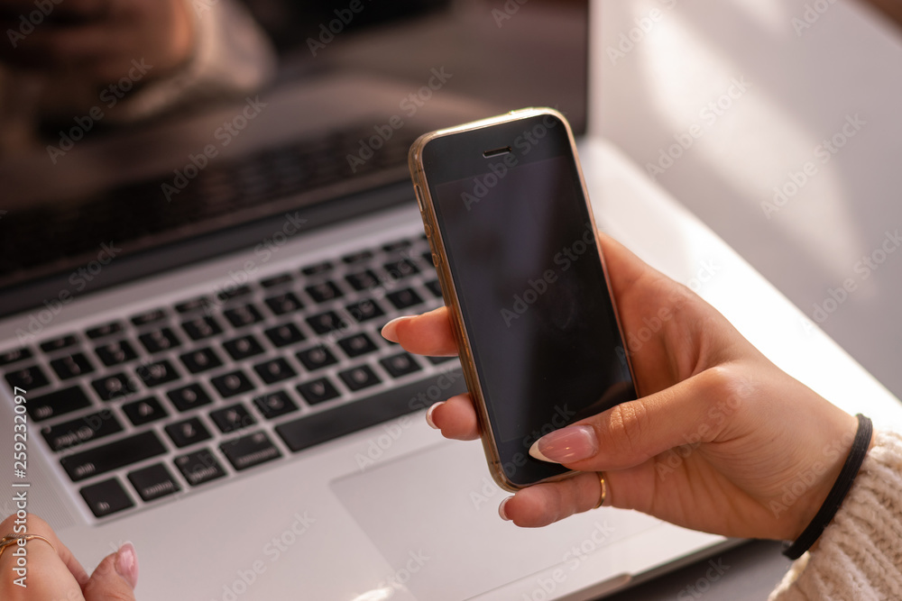 Cropped image of female holding smartphone getting message with confirmation making transaction on laptop computer,woman using mobile phone app for synchronizing data with netbook via bluetooth Cropped image of female holding smartphone getting message with confirmation making transaction on laptop computer,woman using mobile phone app for synchronizing data with netbook via bluetooth