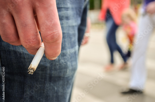 Teenager under eighteen or young man is holding burning cigarette in his hand. Concept of unhealthy lifestyle, addiction and irresponsible parents.