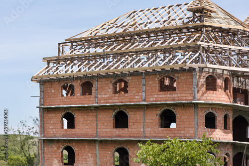 District for rich people with traditional, large gypsy house with luxury decorations and ornaments on the roof in Huedin, Romania. Houses being under construction. Concept of bankruptcy, and abandoned photo