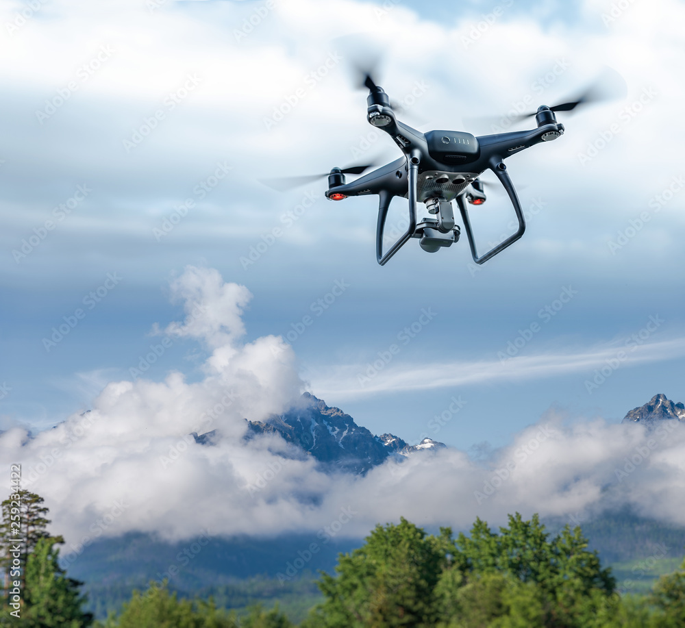 Modern drone flies in the mountains. Dark drone in the air against the backdrop of a mountain landscape. Modern drone flies in the mountains. Dark drone in the air against the backdrop of a mountain landscape.