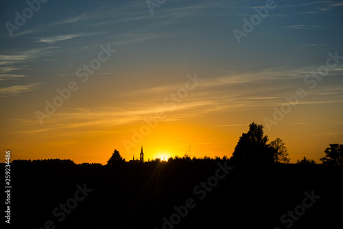 Silhouette of church and city on sunset or sunrise background. 