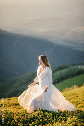 woman in a wedding dress runs across the field toward the mountains © wolfhound911