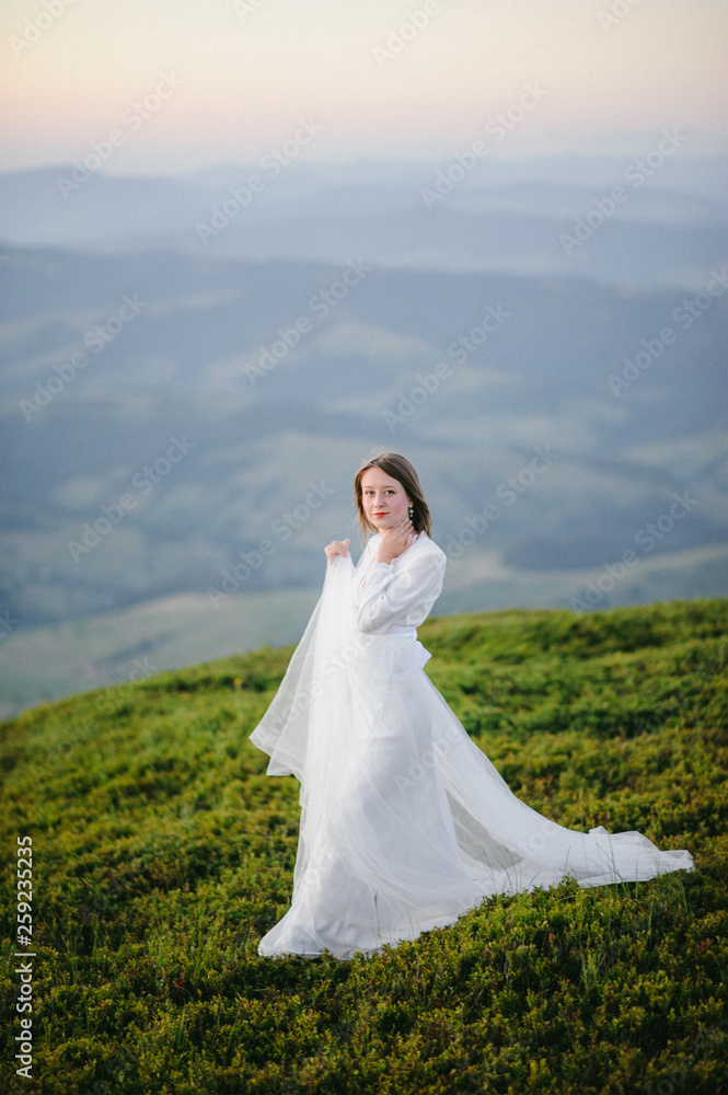 woman in a wedding dress runs across the field toward the mountains