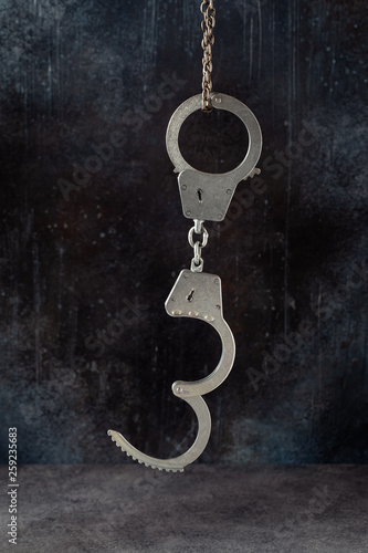 Handcuffs hanging against a grunge dark background