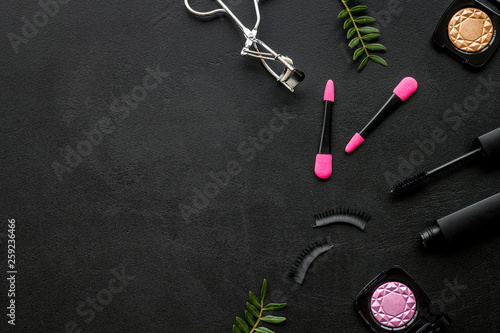 female desk with decorative cosmetic on black background flatlay copyspace