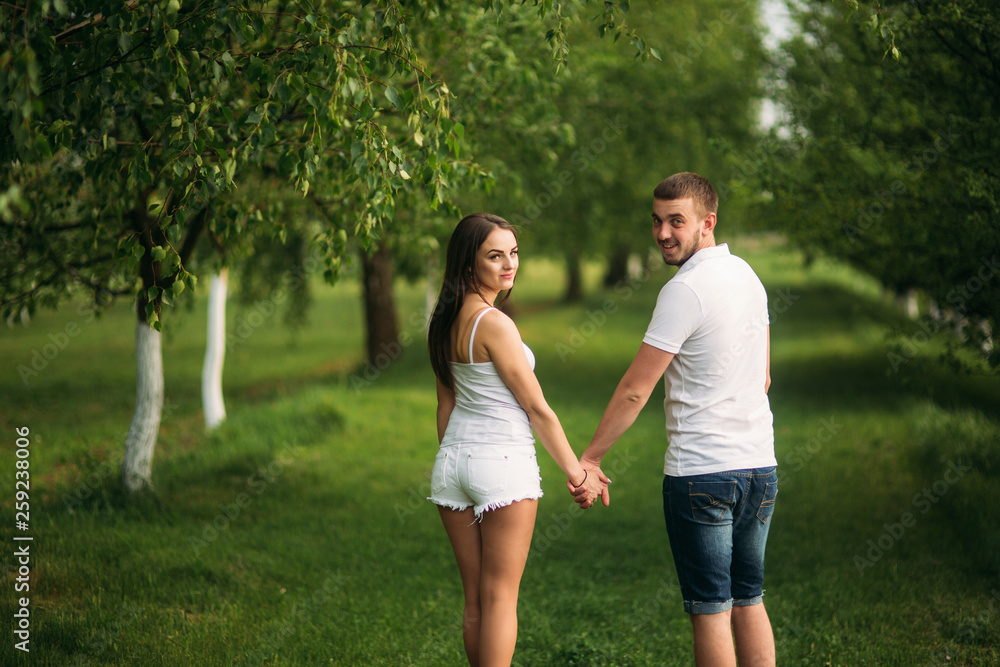 Man and girl walking around the park. Beautiful couple