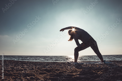 young woman doing yoga and stretching on the shore