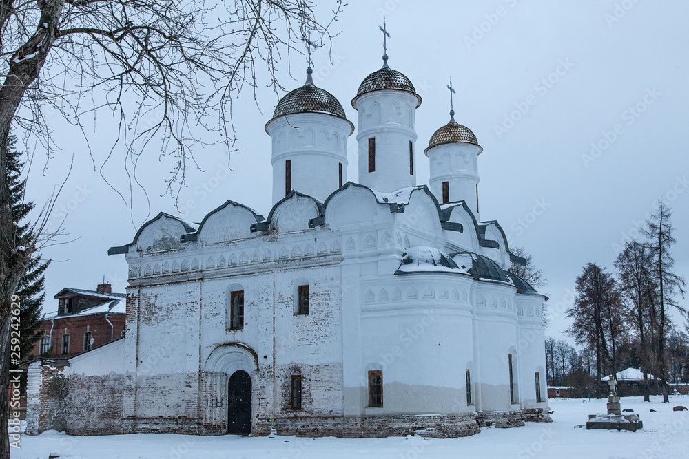 White stone church with golden domes on the background of a dark sky