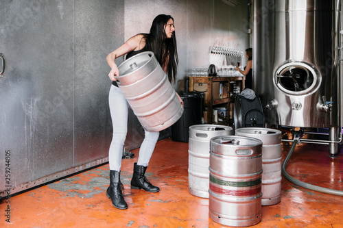 Woman lifting keg in brewery