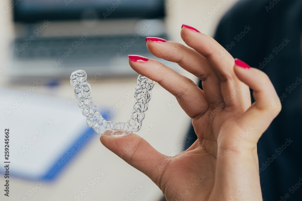 Doctor hand holding a clear dental aligner Stock Photo | Adobe Stock