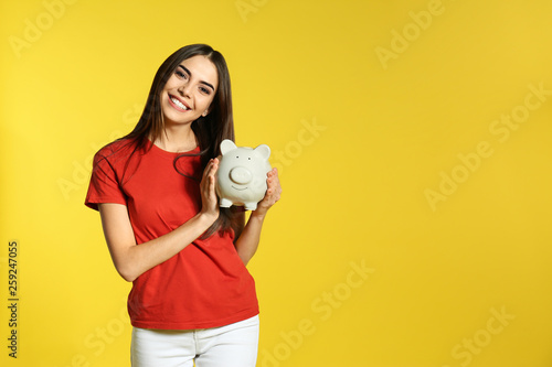 Young woman with piggy bank on color background, space for text. Money saving photo