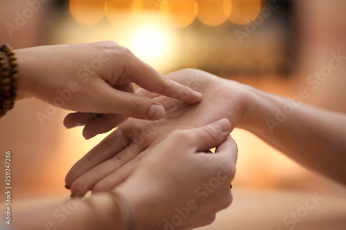 Tableau sur toile Chiromancer reading lines on woman's palm at table, closeup