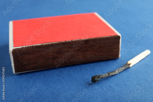 Red box and burnt match on color background, closeup