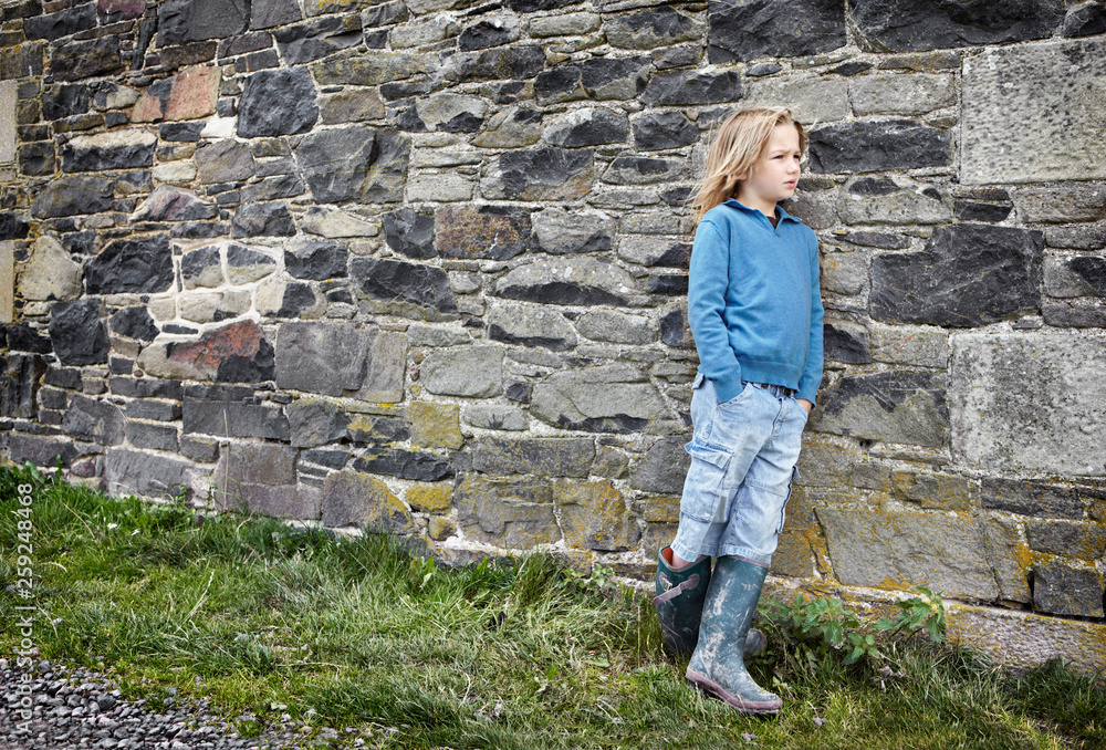 A boy leans against an old stone wall A boy leans against an old stone wall