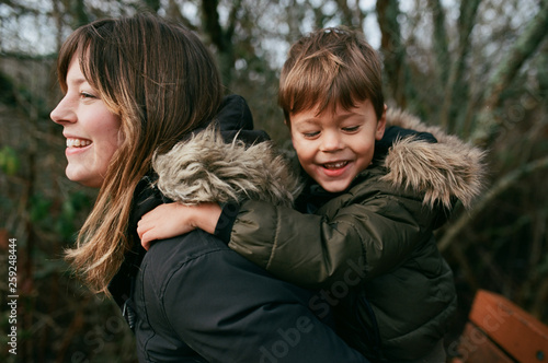 Young mother carrying son outside in nature during winter photo