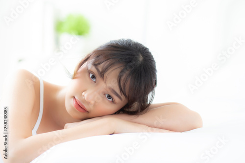 Lifestyle beautiful portrait young asian woman relax lying sleep and smile while wake up with sunrise at morning  girl with happy and fun in the bedroom  health and wellness concept.