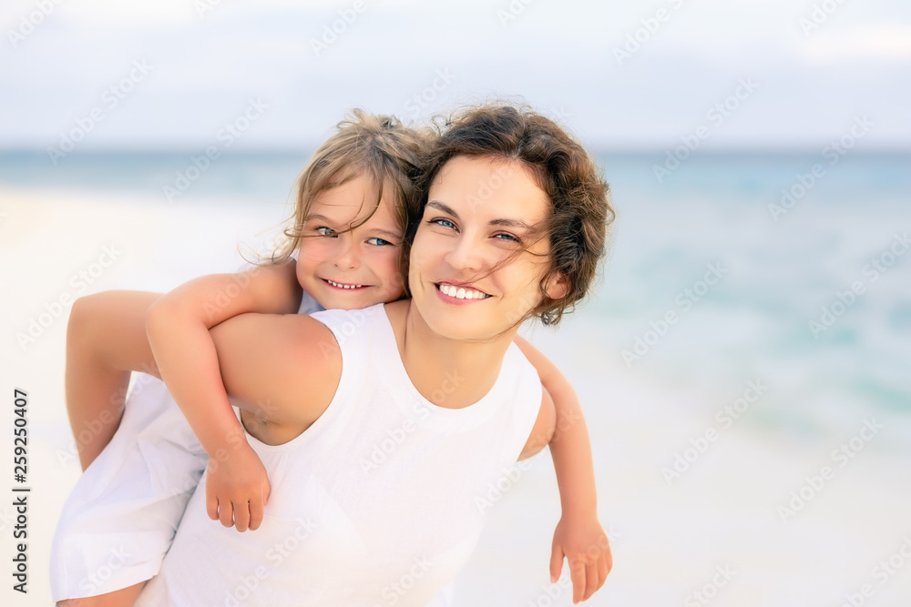 Portrait of happy mother and little daughter on sunny beach on Maldives at summer vacation Portrait of happy mother and little daughter on sunny beach on Maldives at summer vacation