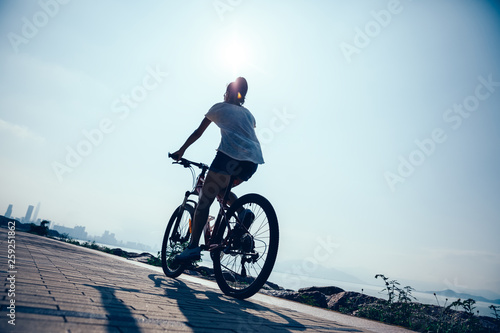 Fototapeta Naklejka Na Ścianę i Meble -  Woman cyclist riding Mountain Bike on sunrise seaside